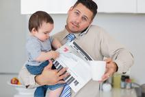 father on phone while holding son