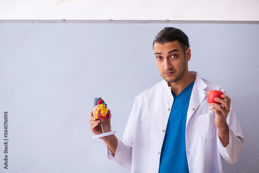 teacher holding an apple and a diagram of a heart